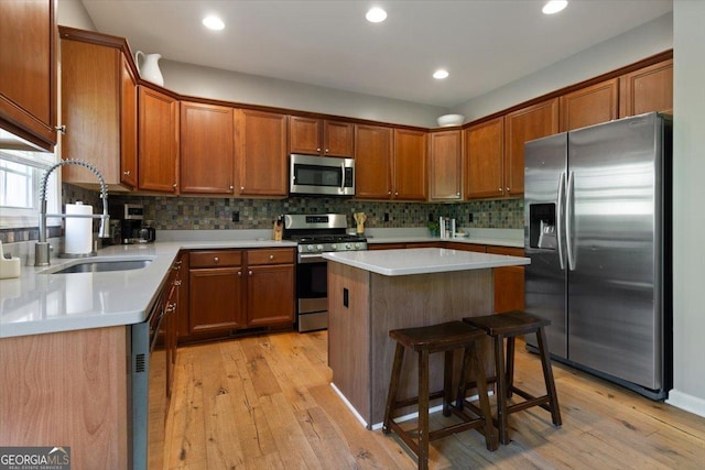 kitchen featuring a sink, appliances with stainless steel finishes, light wood-style floors, and a kitchen island