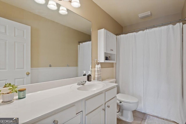 full bathroom with vanity, tile patterned flooring, toilet, and a wainscoted wall