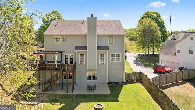 rear view of property featuring a chimney, a lawn, a deck, a gate, and a fenced backyard