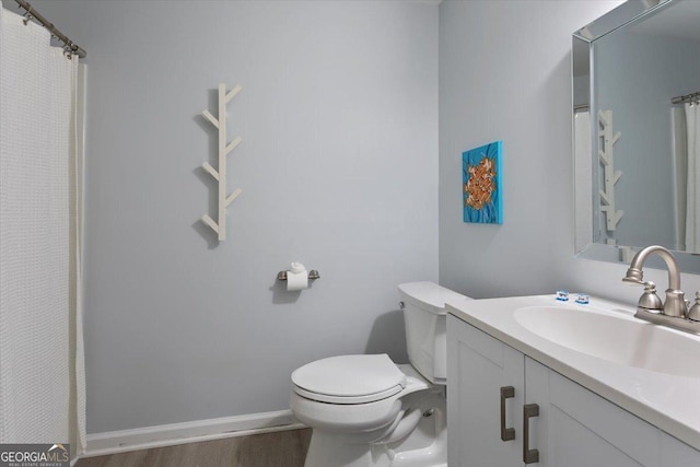 bathroom featuring toilet, baseboards, wood finished floors, and vanity