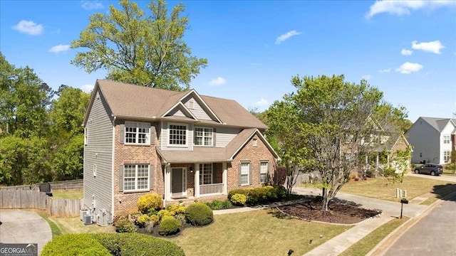 traditional-style house featuring brick siding, a front lawn, fence, and central air condition unit