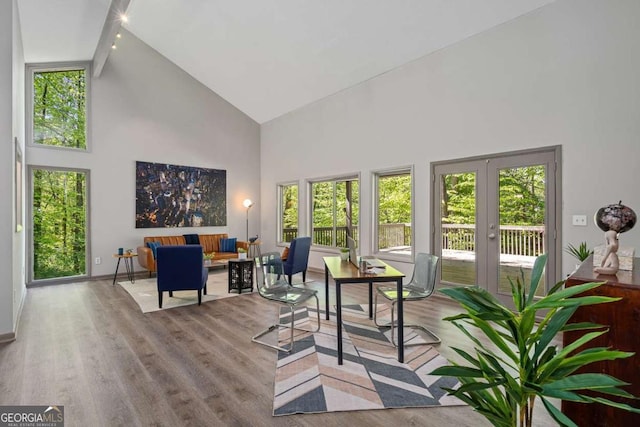 office space featuring french doors, beam ceiling, baseboards, wood finished floors, and high vaulted ceiling