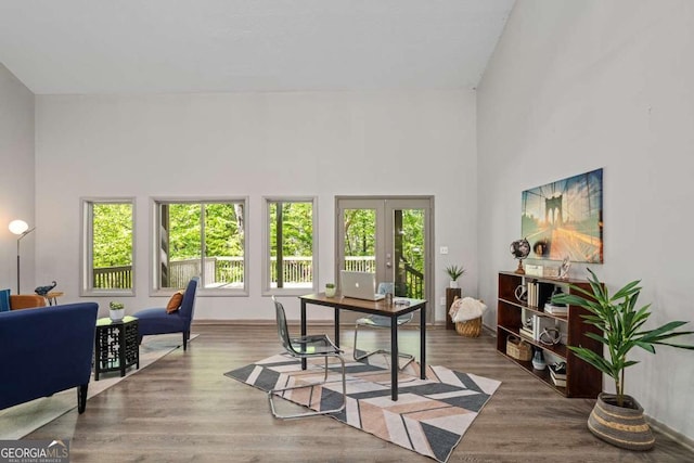 office featuring a towering ceiling, french doors, and wood finished floors