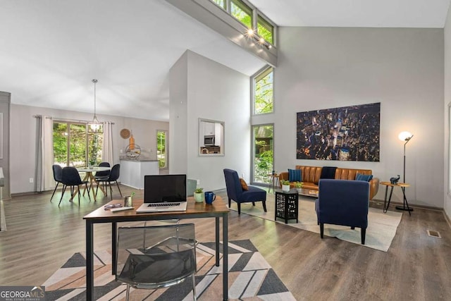 office space with wood finished floors, a high ceiling, baseboards, and visible vents