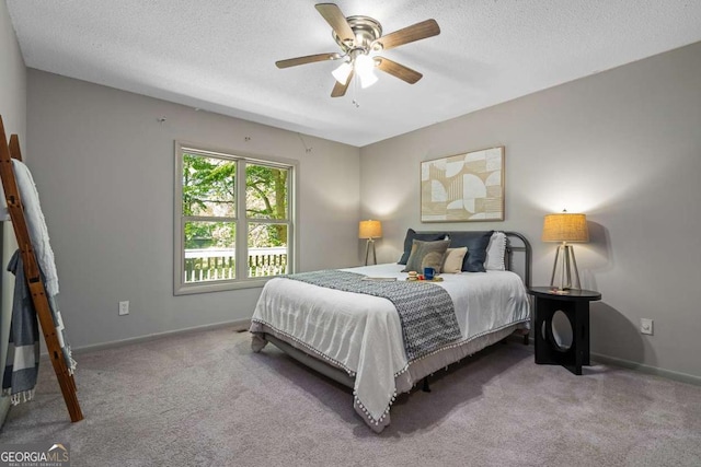 carpeted bedroom with a textured ceiling, a ceiling fan, and baseboards