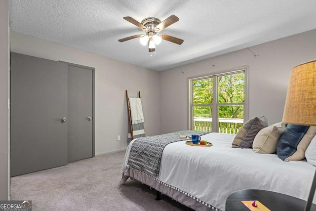bedroom with carpet floors, a ceiling fan, and a textured ceiling