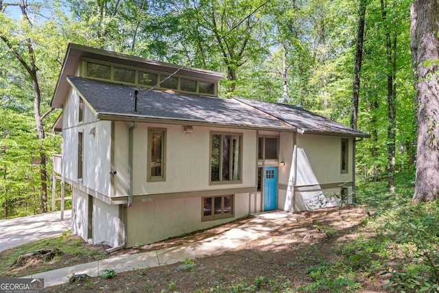 back of house featuring concrete driveway and a shingled roof