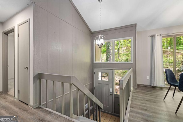 entryway featuring vaulted ceiling, an inviting chandelier, wood finished floors, and a wealth of natural light