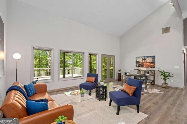 living room featuring french doors, baseboards, visible vents, wood finished floors, and high vaulted ceiling
