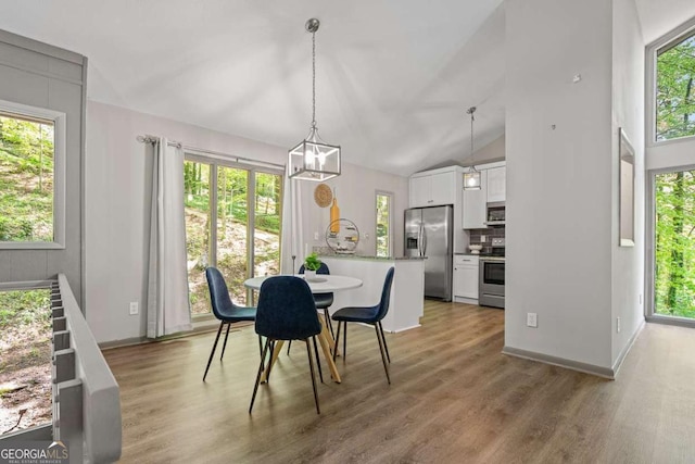 dining room with lofted ceiling, baseboards, a chandelier, and light wood-style floors