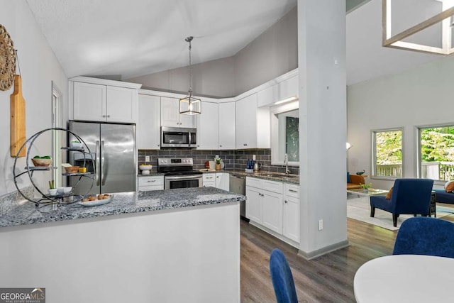 kitchen featuring a sink, stone countertops, appliances with stainless steel finishes, a peninsula, and dark wood-style flooring