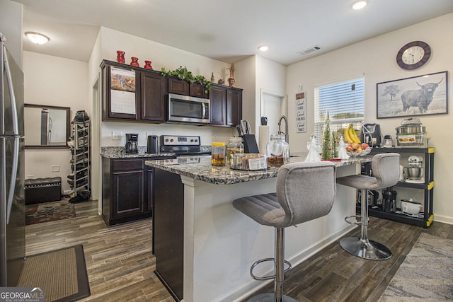 129 Coldwater Way, Griffin, GA 30224 - kitchen featuring appliances with stainless steel finishes, dark wood-style floors, visible vents, and a kitchen bar