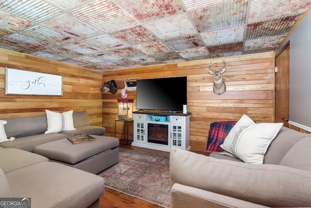 living area with wood walls, a glass covered fireplace, and wood finished floors