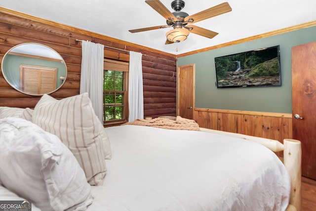 bedroom featuring ceiling fan, log walls, ornamental molding, and a wainscoted wall