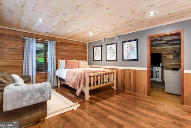 bedroom with wood ceiling, visible vents, light wood finished floors, and wooden walls
