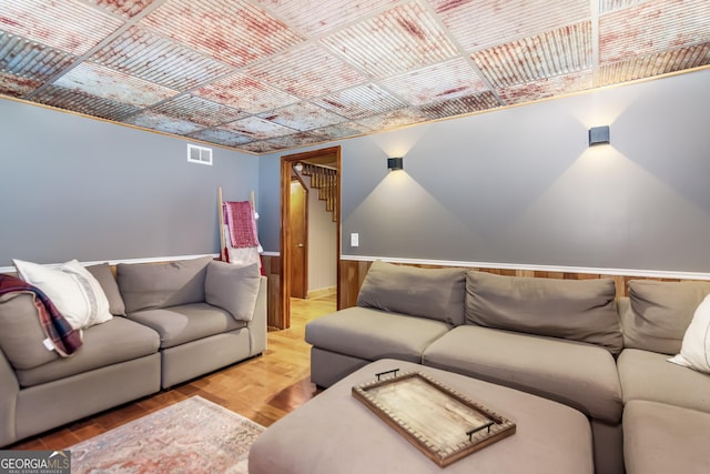 living area with baseboards, wood finished floors, visible vents, and an ornate ceiling
