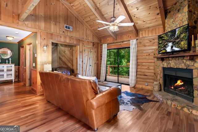 living room featuring wood finished floors, visible vents, a stone fireplace, beam ceiling, and wood ceiling