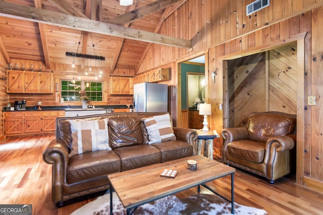 living area featuring wooden walls, visible vents, light wood finished floors, and wooden ceiling