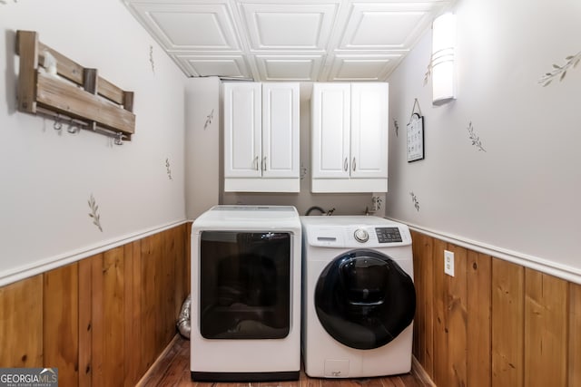 clothes washing area featuring cabinet space, independent washer and dryer, a wainscoted wall, and wood walls