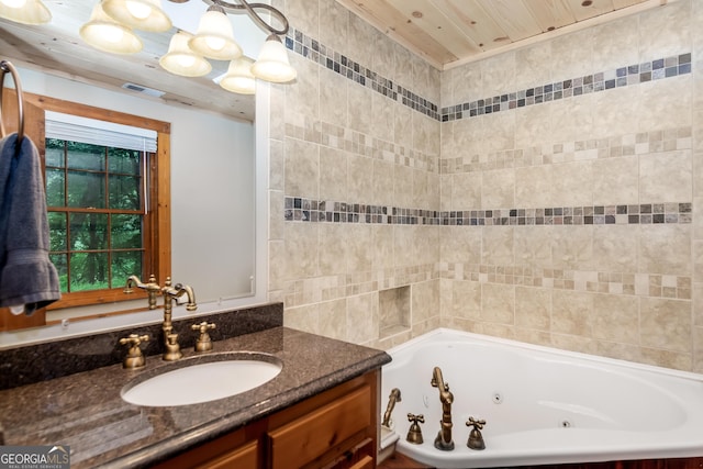 bathroom with vanity, a tub with jets, and visible vents