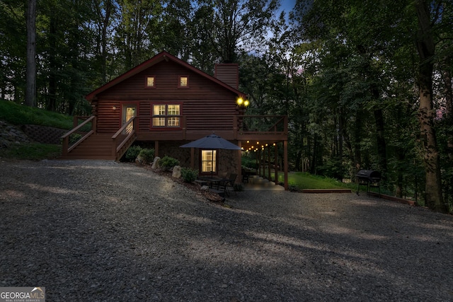 rustic home featuring a chimney, stairway, a deck, and log siding