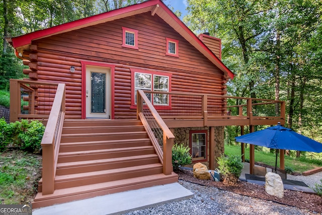 back of property with stairway, a chimney, log exterior, and a deck