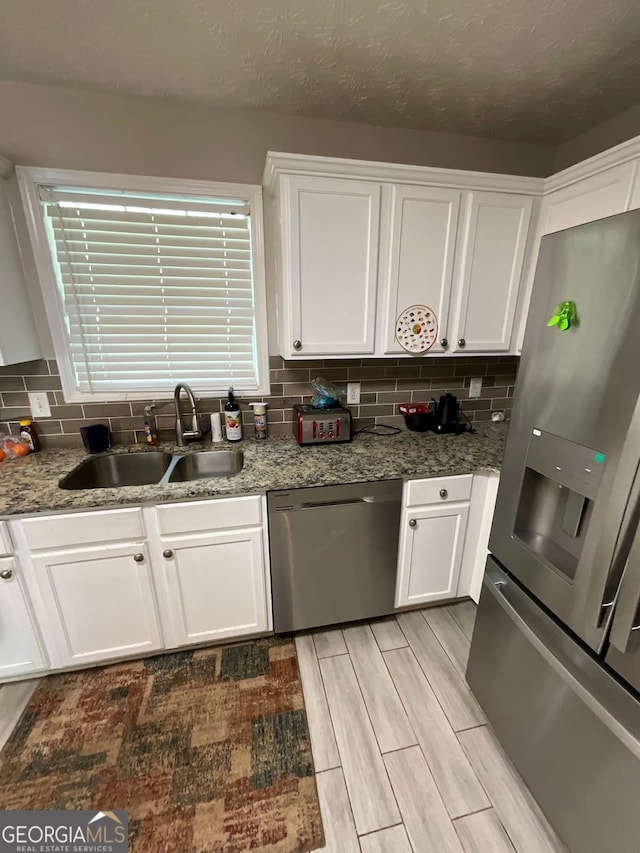 1086 Deshon Trl, Lithonia, GA 30058 - kitchen with stainless steel appliances, a sink, white cabinetry, tasteful backsplash, and wood finish floors