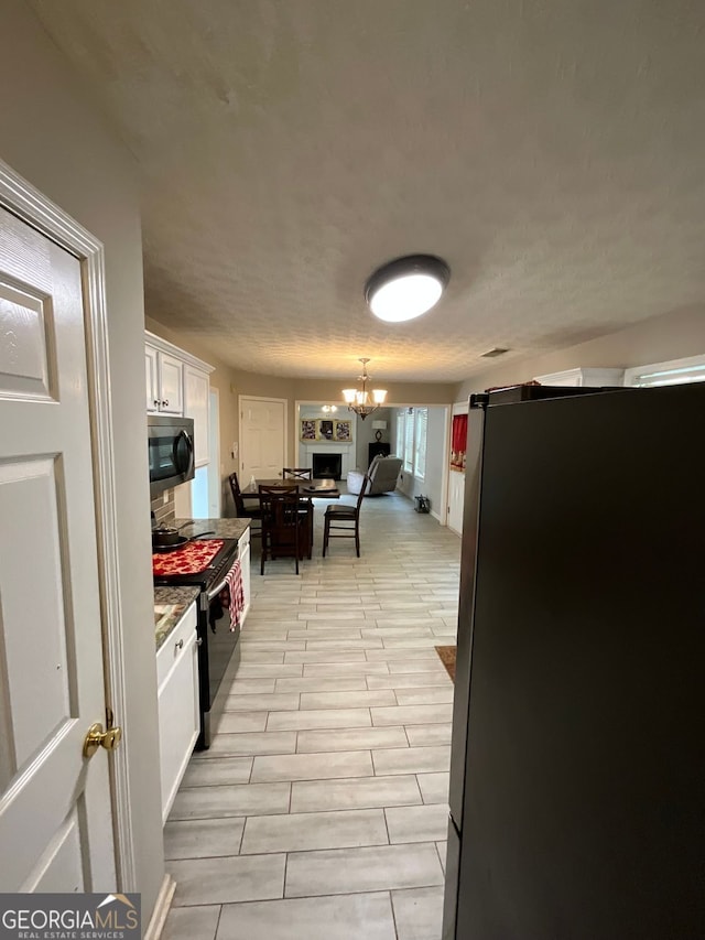 1086 Deshon Trl, Lithonia, GA 30058 - kitchen with white cabinetry, a chandelier, and black / electric stove