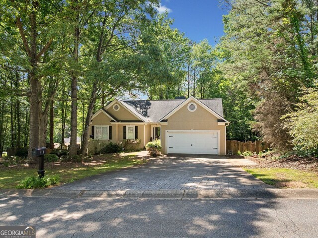 614 Springharbor Dr, Woodstock, GA 30188 - view of front facade with driveway, an attached garage, fence, and stucco siding