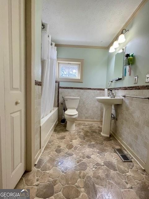 7650 Neese Commerce Rd, Hull, GA 30646 - bathroom with a wainscoted wall, stone finish floors, toilet, tile walls, and a textured ceiling