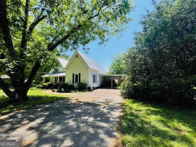 7650 Neese Commerce Rd, Hull, GA 30646 - view of property exterior featuring driveway, a lawn, metal roof, and a carport