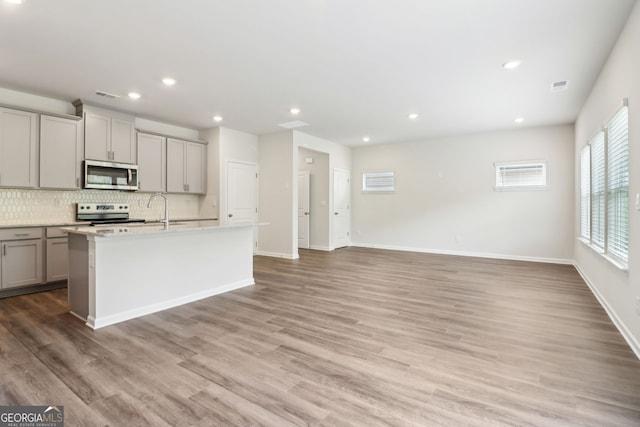 2762 Aralynn Way, College Park, GA 30337 - kitchen with stainless steel appliances, tasteful backsplash, visible vents, an island with sink, and gray cabinetry