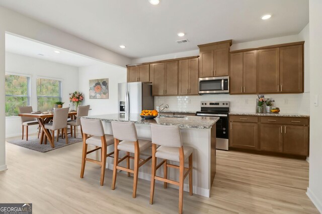 2764 Aralynn Way, College Park, GA 30337 - kitchen featuring light wood-style flooring, a kitchen bar, visible vents, backsplash, and appliances with stainless steel finishes