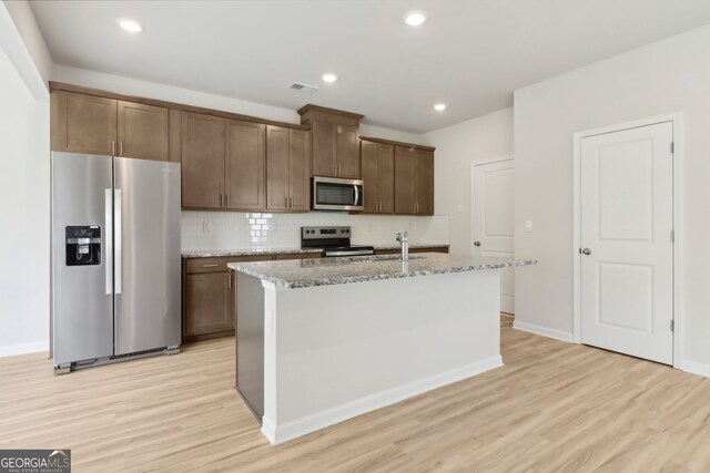 2764 Aralynn Way, College Park, GA 30337 - kitchen with light wood-type flooring, stainless steel appliances, an island with sink, and backsplash