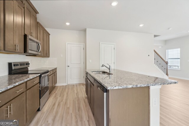 2764 Aralynn Way, College Park, GA 30337 - kitchen featuring appliances with stainless steel finishes, an island with sink, a sink, tasteful backsplash, and light wood-type flooring