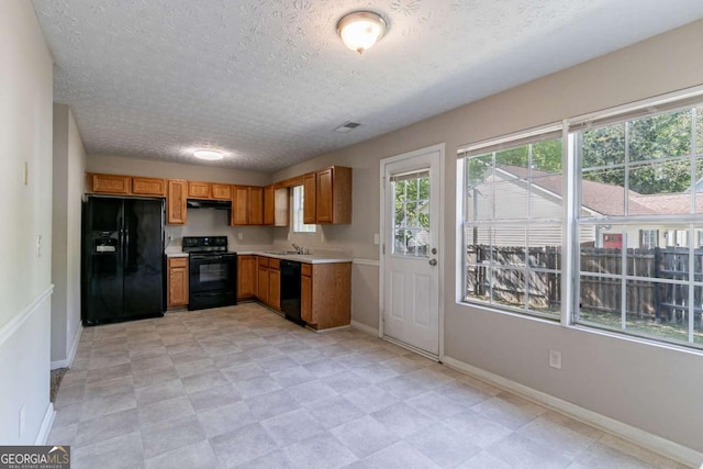 805 Old Rocky Rd, Atlanta, GA 30349 - kitchen with light countertops, under cabinet range hood, a wealth of natural light, and black appliances