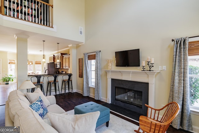 living area featuring visible vents, a healthy amount of sunlight, a high end fireplace, and dark wood finished floors