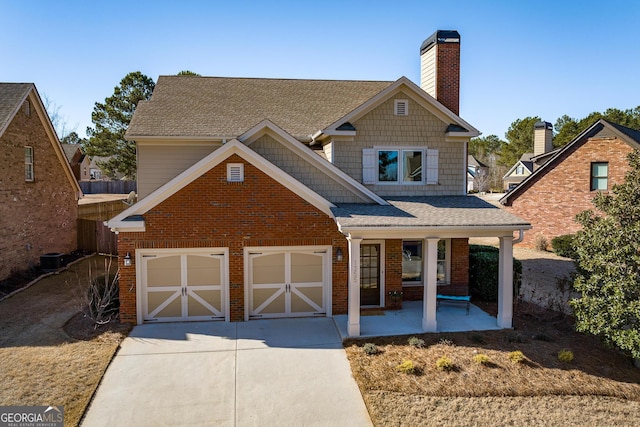 view of front facade with concrete driveway, brick siding, a chimney, and a porch