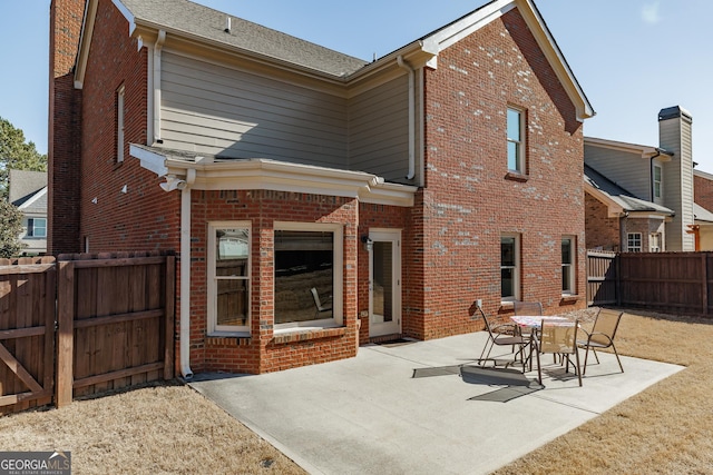 rear view of house with a fenced backyard, a patio, and brick siding