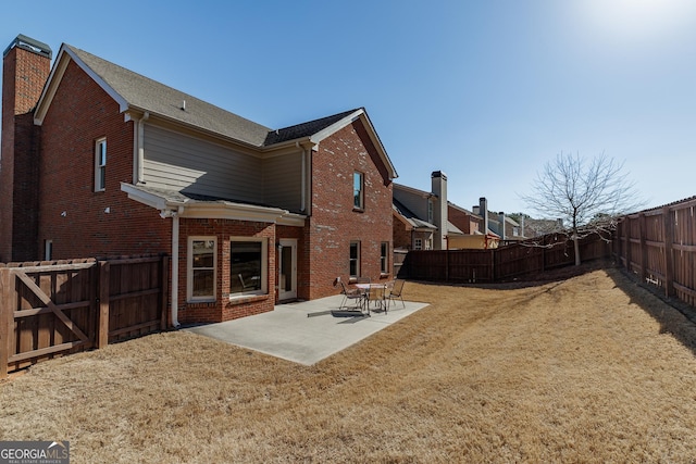 rear view of property featuring a gate, brick siding, a fenced backyard, a yard, and a patio