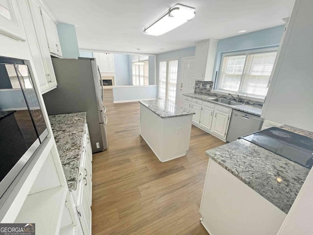 kitchen with light wood finished floors, a center island, white cabinetry, and appliances with stainless steel finishes