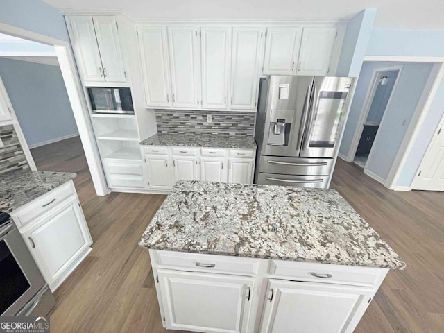 kitchen featuring dark wood finished floors, light stone countertops, decorative backsplash, stainless steel fridge, and white cabinetry
