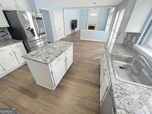 kitchen featuring stainless steel fridge with ice dispenser, white cabinetry, a sink, a fireplace, and dark wood-style flooring