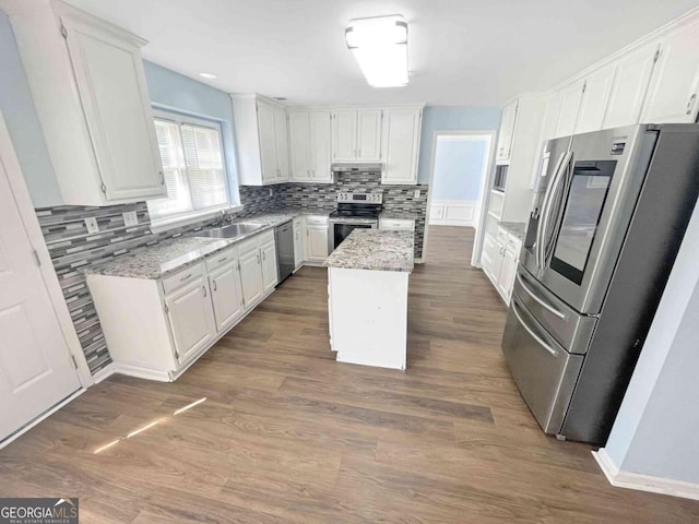 kitchen with a sink, a center island, tasteful backsplash, appliances with stainless steel finishes, and white cabinetry