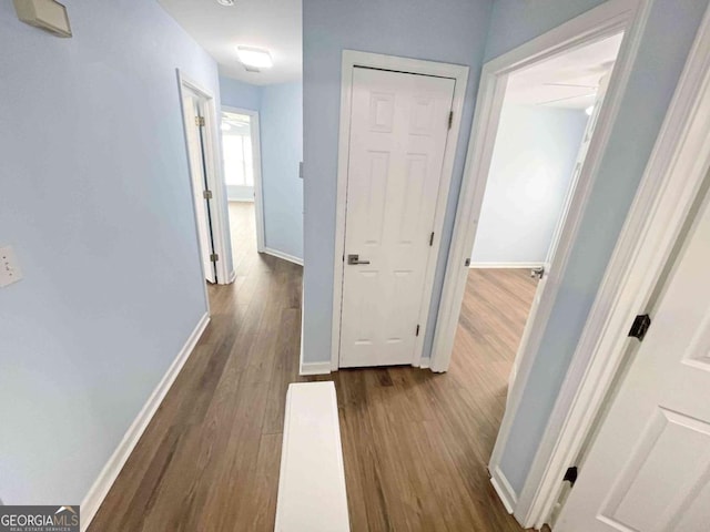 corridor featuring baseboards and dark wood-style flooring