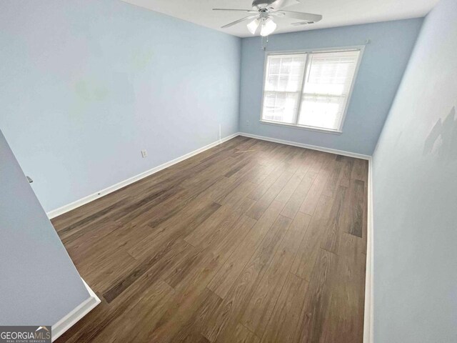 unfurnished room with baseboards, a ceiling fan, visible vents, and dark wood-style floors