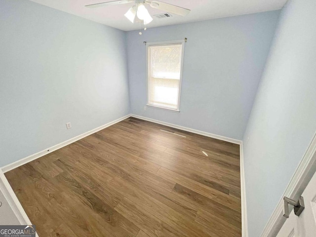 spare room featuring baseboards, a ceiling fan, wood finished floors, and visible vents