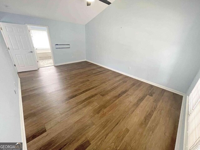 empty room with dark wood finished floors, vaulted ceiling, baseboards, and ceiling fan