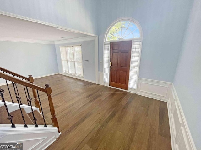foyer entrance featuring wood finished floors, crown molding, and stairs