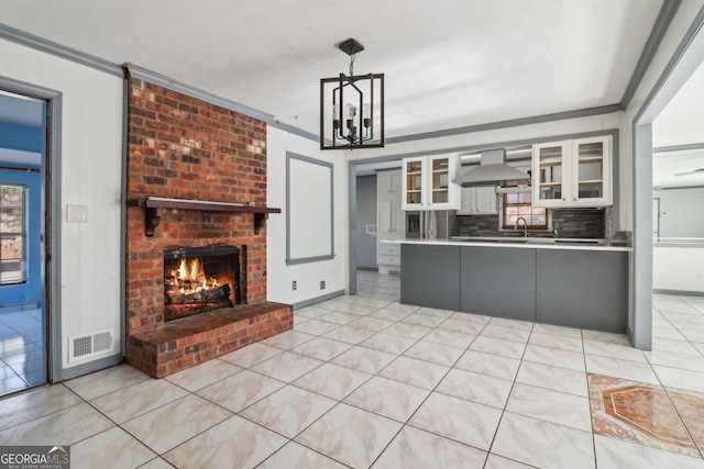 kitchen with light countertops, visible vents, wall chimney exhaust hood, a fireplace, and glass insert cabinets